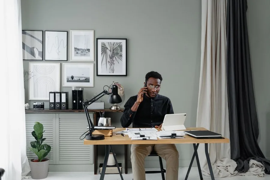 A self-employed landlord working from a home office, managing rental and side-business records on a tablet