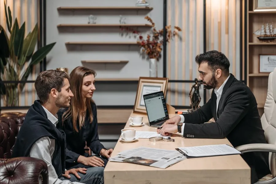 An accountant talking a couple through their National Insurance contributions across paperwork and a laptop