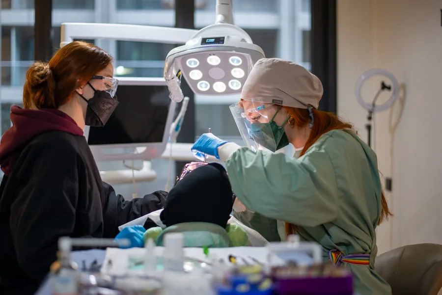 A dentist and assistant in PPE treating a patient in a modern UK NHS dental surgery A dentist and assistant in PPE treating a patient in a modern UK NHS dental surgery