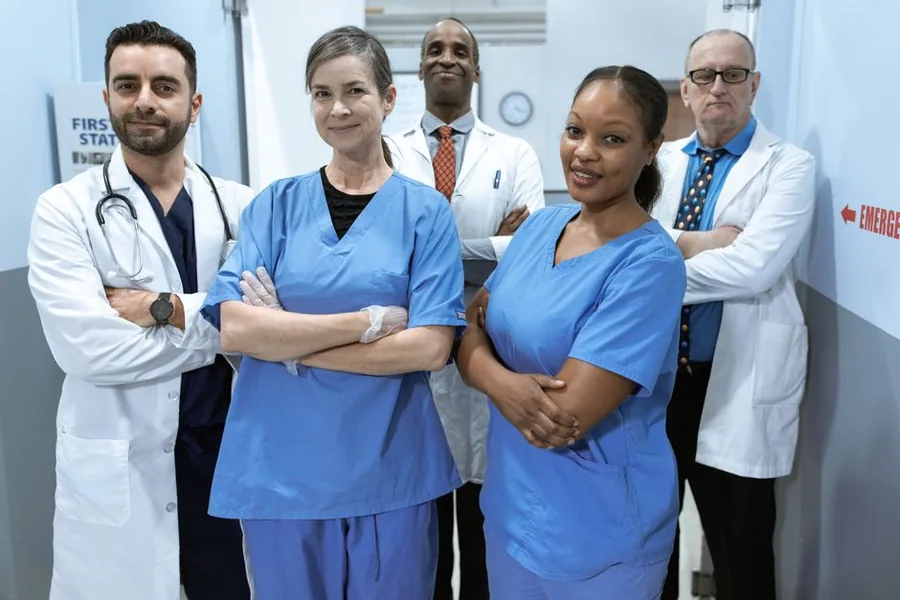 A clinical team standing together in an NHS hospital corridor, representing the trust that issues a locum's IR35 status determination A clinical team standing together in an NHS hospital corridor, representing the trust that issues a locum's IR35 status determination