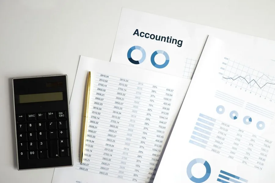 Accounting worksheets, financial charts and a calculator laid out on a desk for a small business review