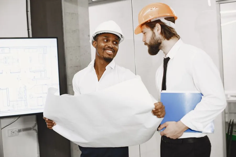 Two UK contractors in hard hats reviewing project plans on site, the sort of self-employed workers assessing their IR35 status