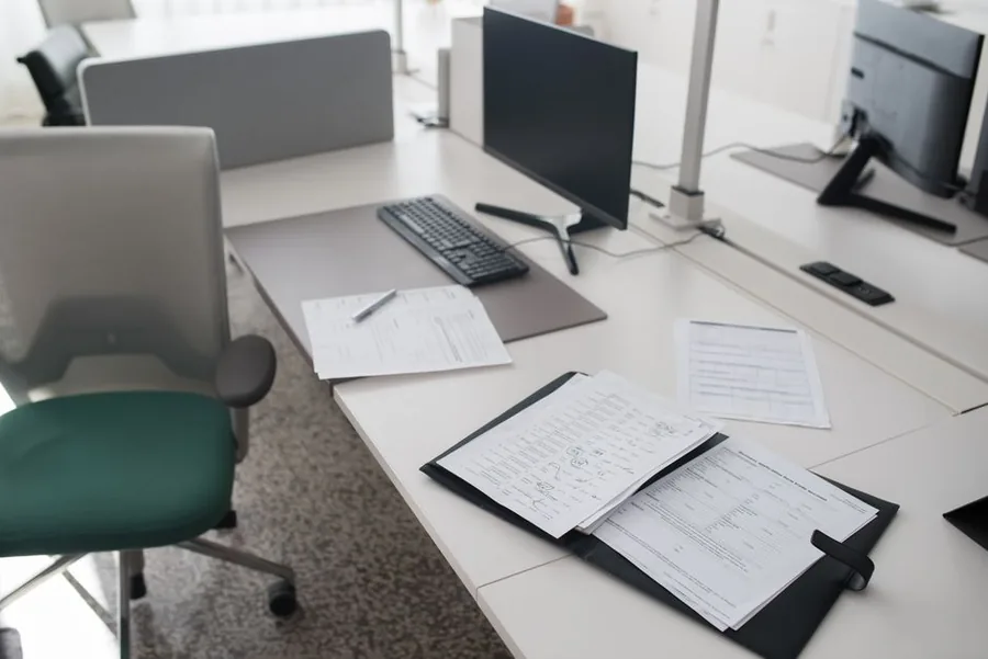 Printed payroll forms and a folder spread across a desk in a UK office, ready for an employer to check and file Printed payroll forms and a folder spread across a desk in a UK office, ready for an employer to check and file