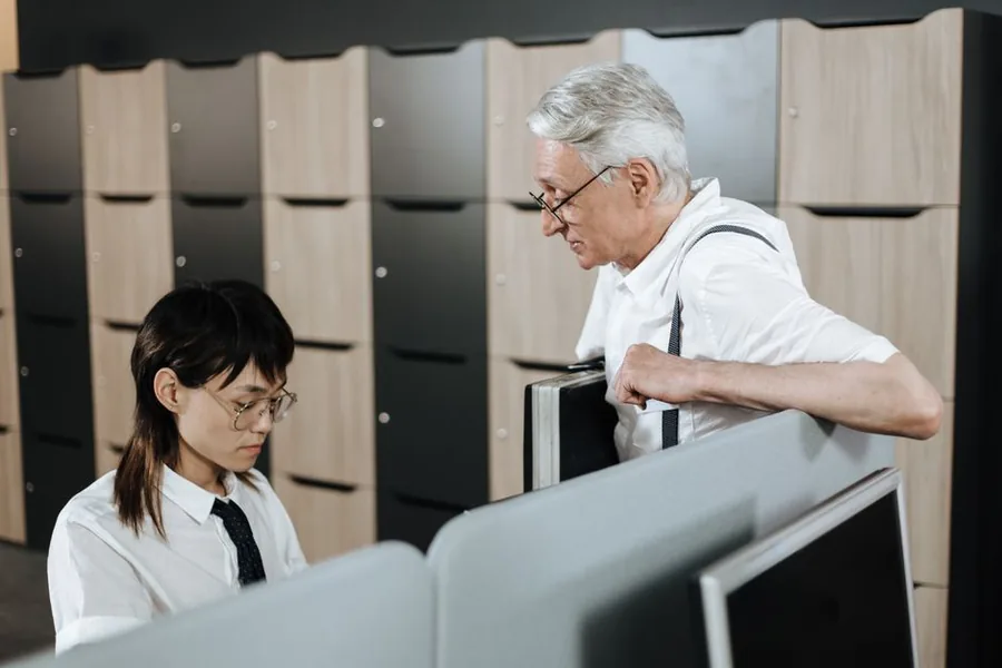An employer handing a departing member of staff their paperwork across an office desk, much like issuing a P45 An employer handing a departing member of staff their paperwork across an office desk, much like issuing a P45