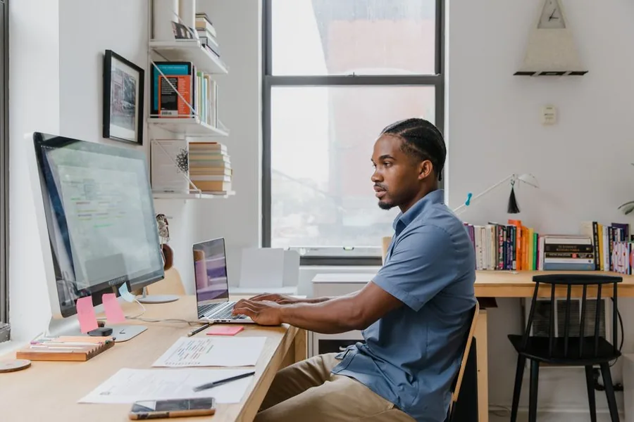 A small business owner reviewing payroll paperwork and a laptop while sorting employee records at a desk A small business owner reviewing payroll paperwork and a laptop while sorting employee records at a desk