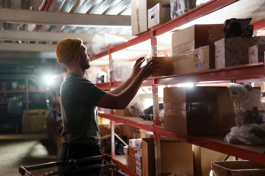 A reseller checking boxed inventory on warehouse shelving, valuing stock brought into the business as opening stock