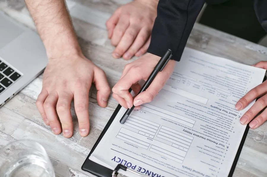 An accountant reviewing the cover terms and previous claims history on a professional indemnity insurance policy form