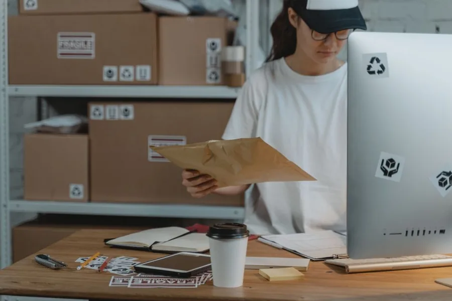 An online store owner at a packing desk reviewing a return, the kind of Shopify refund a seller must record and reverse VAT on