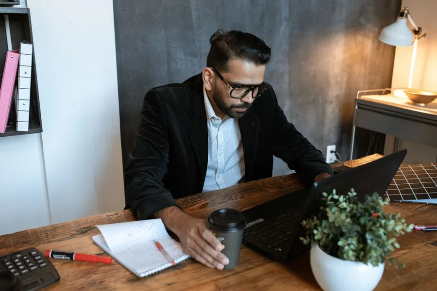 A first-time landlord working through his rental income figures with a calculator and laptop at his desk