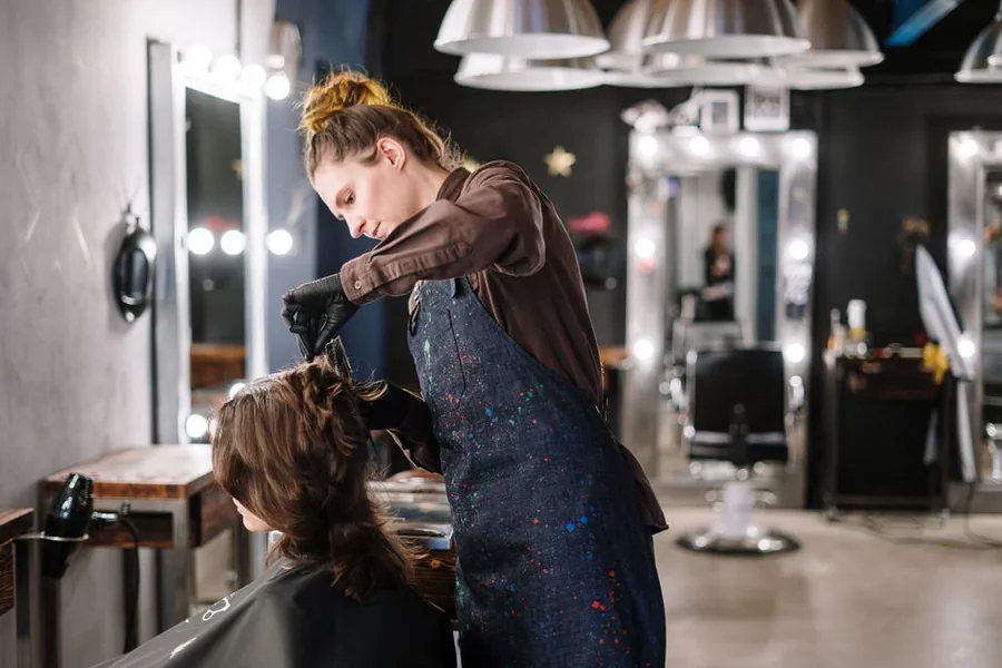 A self-employed hairstylist cutting a client's hair at her rented salon chair A self-employed hairstylist cutting a client's hair at her rented salon chair