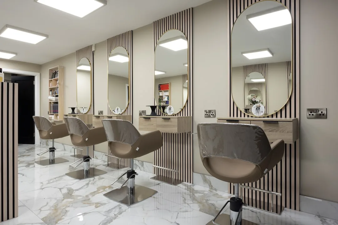 A hairdresser working at a rented chair in a busy salon, styling a client's hair