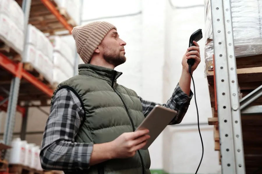 A reseller scanning warehouse stock with a barcode reader and tablet to value inventory without receipts