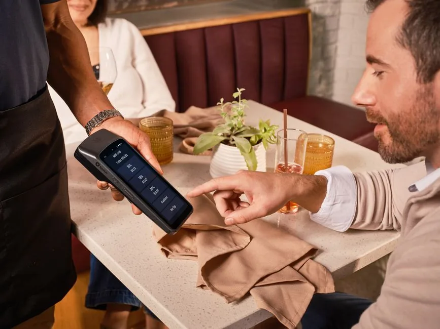 A waiter presenting a card terminal with tip options in pounds as a diner adds a gratuity in a UK restaurant A waiter presenting a card terminal with tip options in pounds as a diner adds a gratuity in a UK restaurant