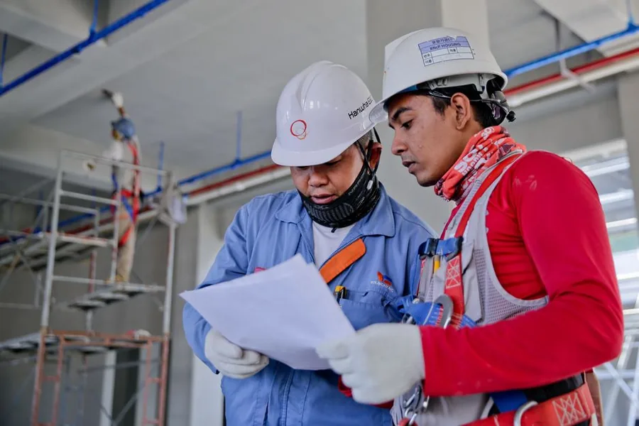 Two construction workers in hard hats checking paperwork on site, the kind of subcontractor job now covered by the VAT reverse charge Two construction workers in hard hats checking paperwork on site, the kind of subcontractor job now covered by the VAT reverse charge