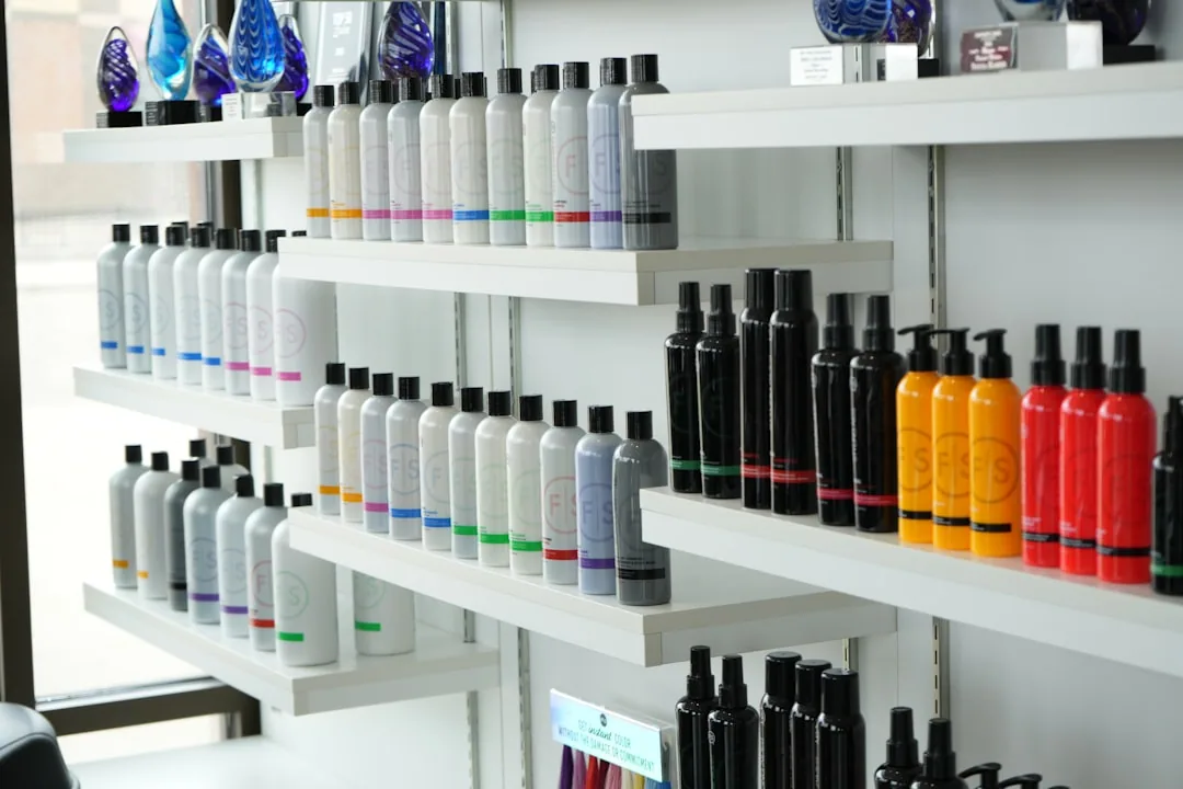 A salon owner arranging shampoo and styling products on a retail shelf while reviewing stock records