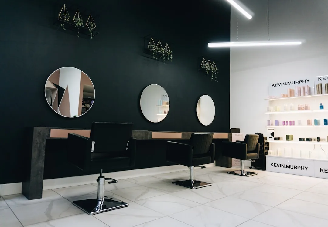 A salon client tipping a hairdresser by card at the reception desk after an appointment