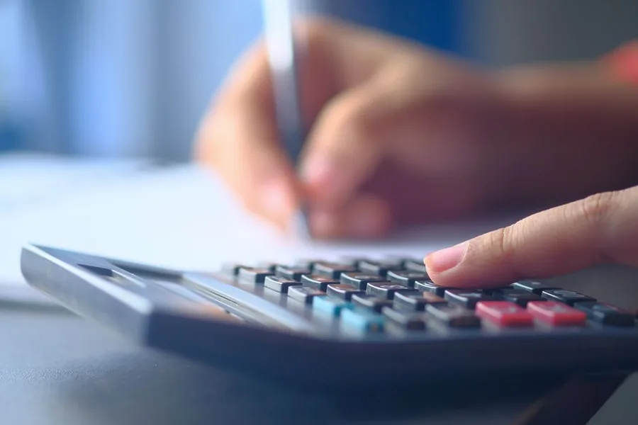 Working out self-employed income tax and National Insurance with a calculator and handwritten figures