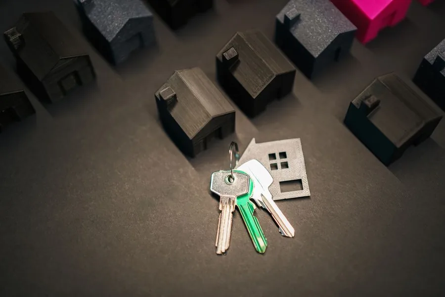 Rows of miniature houses beside a house-shaped keyring, representing a residential property portfolio being transferred into a limited company