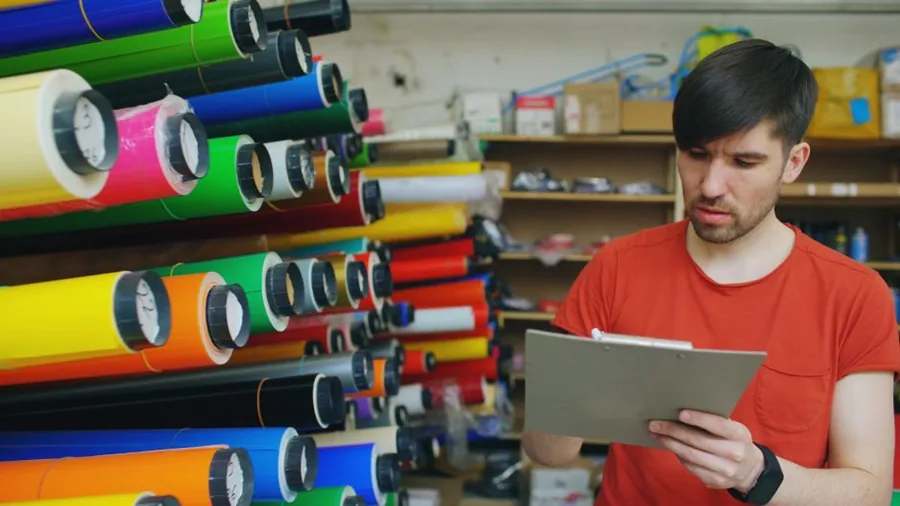 A small online retailer counting shelved stock with a clipboard, the kind of year-end stocktake behind Shopify COGS figures A small online retailer counting shelved stock with a clipboard, the kind of year-end stocktake behind Shopify COGS figures