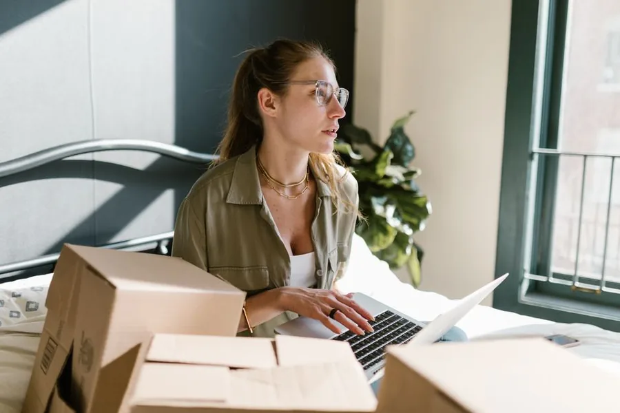 Two UK online store owners reviewing cross-border orders and VAT on a laptop beside packed parcels ready to ship Two UK online store owners reviewing cross-border orders and VAT on a laptop beside packed parcels ready to ship