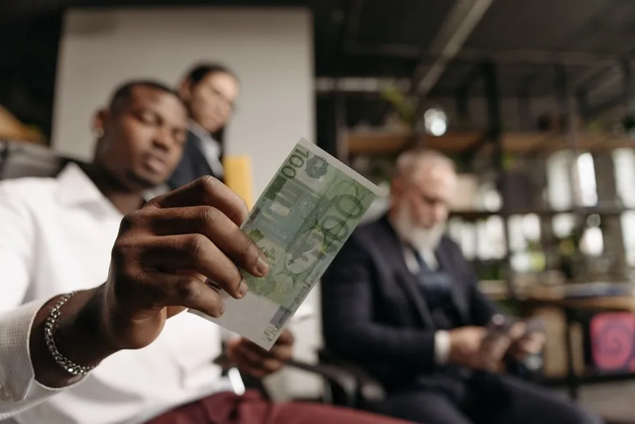 Business colleagues examining a foreign currency note while reviewing overseas sales income Business colleagues examining a foreign currency note while reviewing overseas sales income