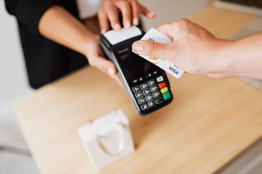 A customer paying by card at a shop till, the kind of retail sale a Shopify POS records before VAT reconciliation A customer paying by card at a shop till, the kind of retail sale a Shopify POS records before VAT reconciliation