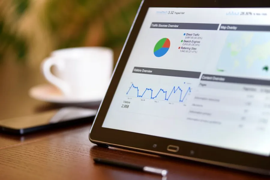An accountant reviewing ecommerce sales and traffic analytics on a tablet dashboard while working through a client's online store figures