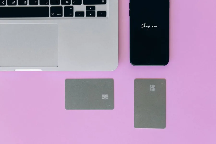 A laptop, a phone reading Shop now and payment cards, the setup behind an online store selling subscriptions on Shopify.