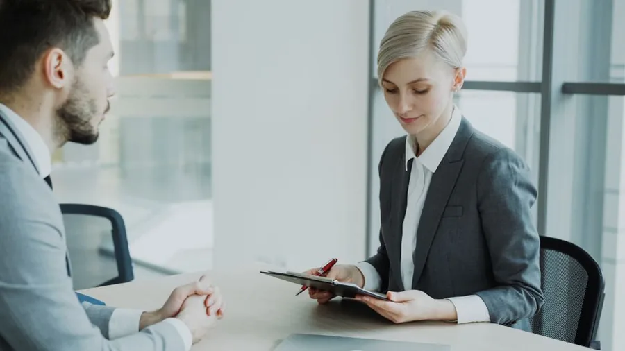 A UK founder meeting a business plan consultant to review planning documents across an office table A UK founder meeting a business plan consultant to review planning documents across an office table