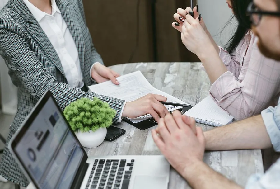 A sole trader going through a business insurance policy with an adviser, laptop and paperwork on the table A sole trader going through a business insurance policy with an adviser, laptop and paperwork on the table