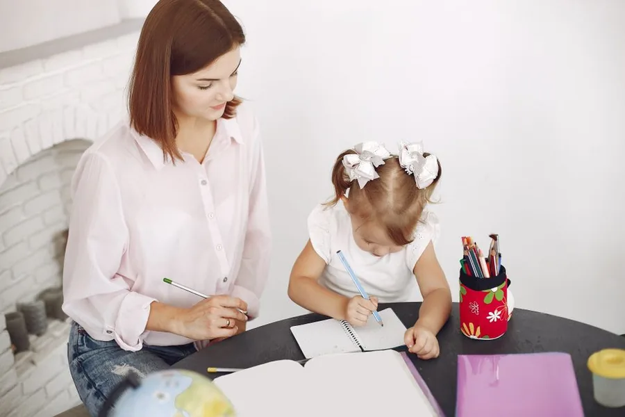 A parent holding her toddler while reviewing her Tax-Free Childcare account on a laptop at home A parent holding her toddler while reviewing her Tax-Free Childcare account on a laptop at home