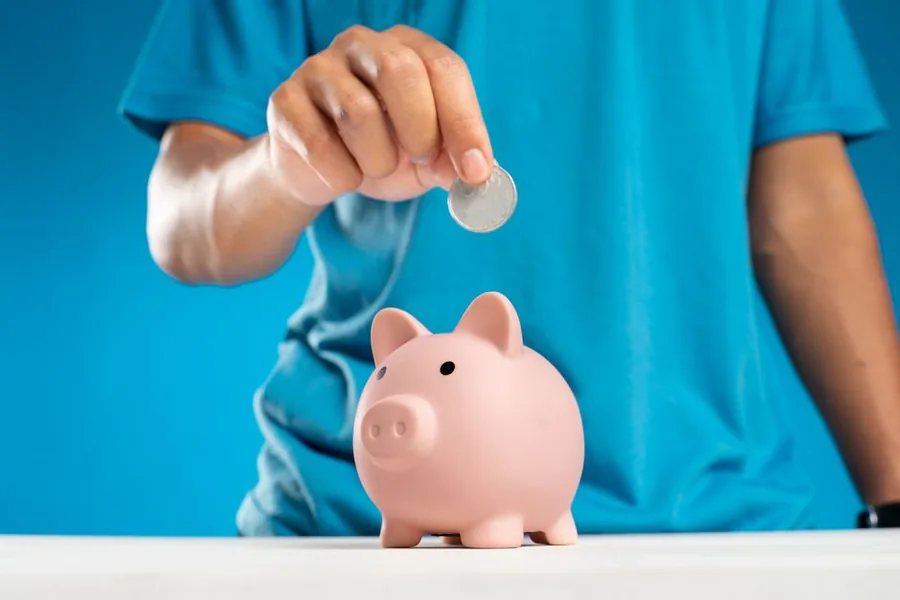 A saver dropping a coin into a piggy bank, building up savings that can earn interest against the personal savings allowance A saver dropping a coin into a piggy bank, building up savings that can earn interest against the personal savings allowance