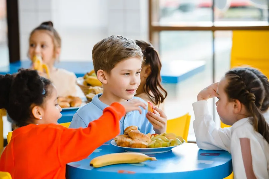 Children sharing a meal of fruit and pastries at a bright cafe table, the kind of spend covered by the temporary 5% VAT rate