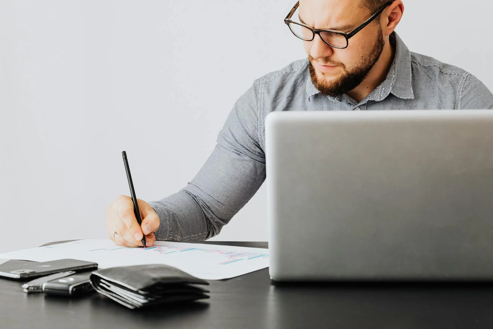 A UK TikTok creator at a desk reviewing commission statements and a calculator while filming content on a ring-lit phone