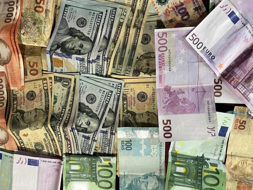 A US dollar bill resting on assorted foreign banknotes, reflecting the multi-currency TikTok payouts a UK creator must convert to sterling