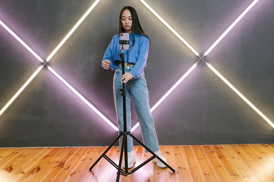 A UK TikTok creator mounting a phone on a tripod in a neon studio, filming content that counts as taxable self-employed income A UK TikTok creator mounting a phone on a tripod in a neon studio, filming content that counts as taxable self-employed income