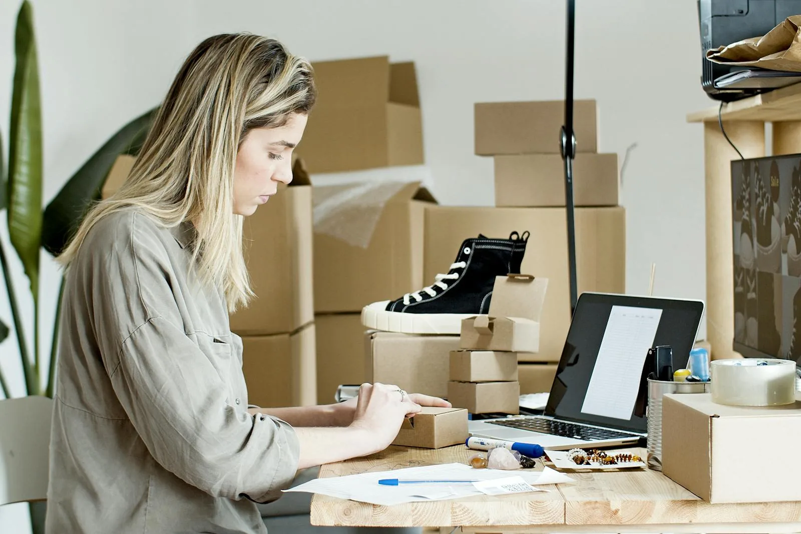 A UK TikTok Shop seller at a desk reviewing a settlement report on a laptop next to accounting software showing sales and fees