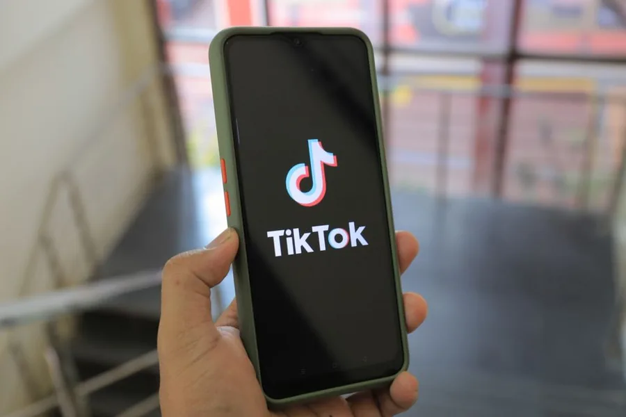 A hand holding a smartphone showing the TikTok app, the platform where UK sellers cross the £90k VAT threshold A hand holding a smartphone showing the TikTok app, the platform where UK sellers cross the £90k VAT threshold
