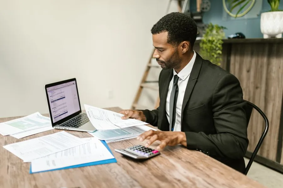 An accountant checking documents against a calculator to confirm a seller's tax details and release blocked TikTok Shop payouts
