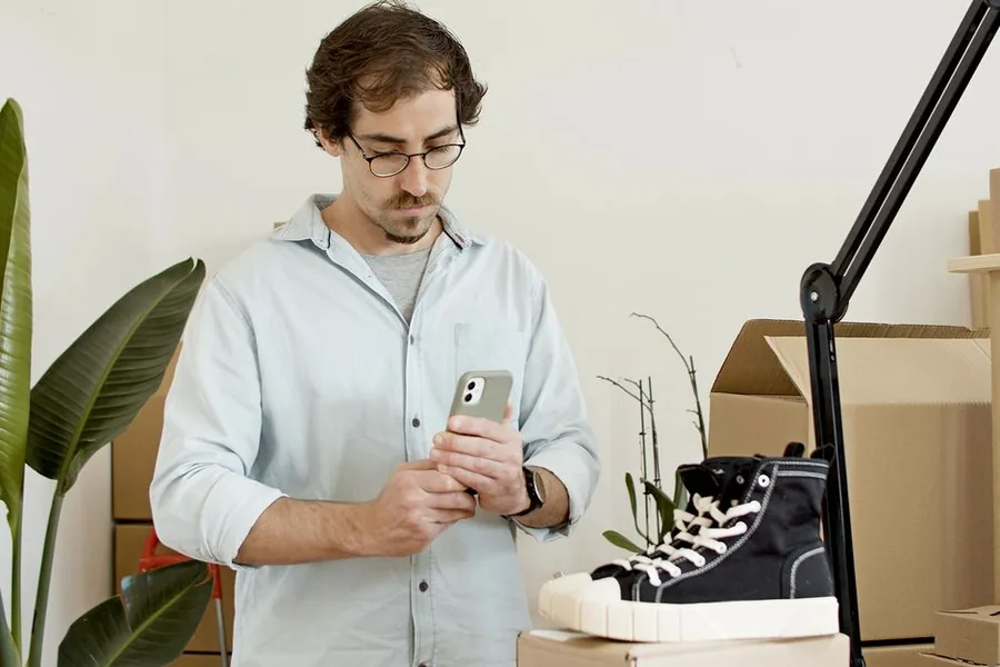 A UK online seller photographing trainers with a smartphone to list the product for sale A UK online seller photographing trainers with a smartphone to list the product for sale