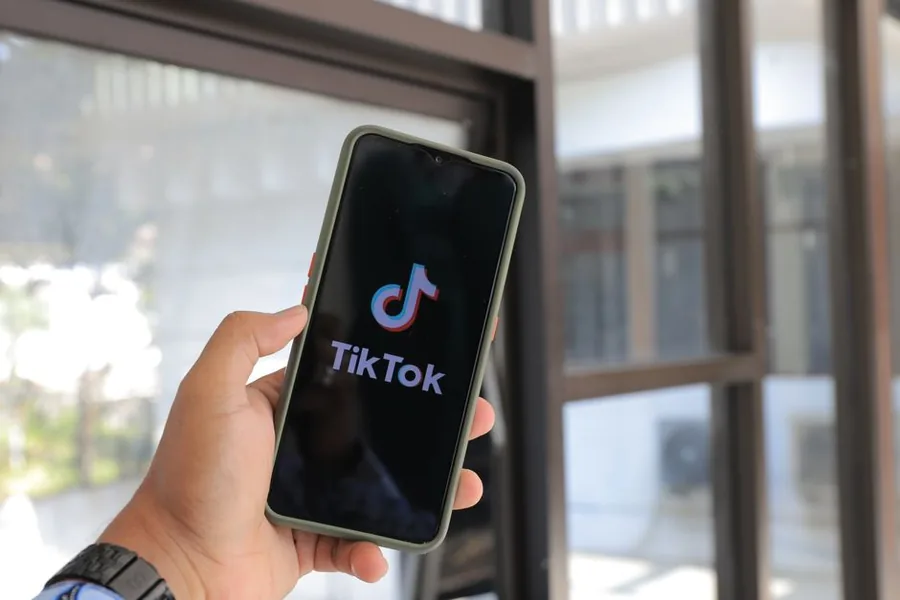 A UK seller opening TikTok on a phone before reconciling Shop settlement payouts against the books A UK seller opening TikTok on a phone before reconciling Shop settlement payouts against the books