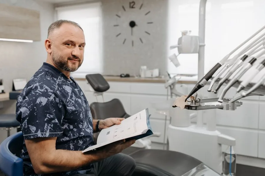 A dental practice principal reviewing records in the surgery, where UDA shortfalls can trigger clawback in the practice accounts