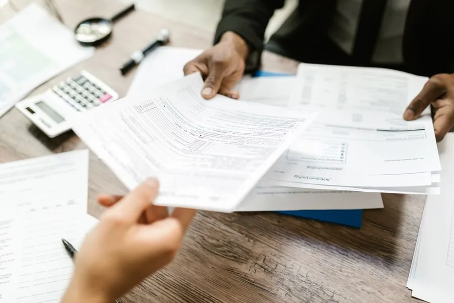 A client handing financial paperwork to an accountant to review their income tax position across the 2025/26 bands A client handing financial paperwork to an accountant to review their income tax position across the 2025/26 bands