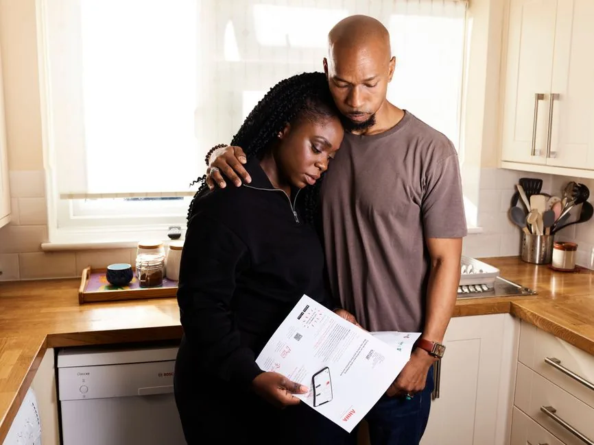 A UK couple at home going through a pay statement together, checking their deductions and take-home pay A UK couple at home going through a pay statement together, checking their deductions and take-home pay