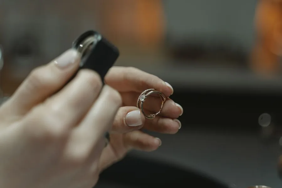 A jeweller inspecting a pre-owned diamond ring through a loupe before resale, the kind of stock covered by the VAT margin scheme