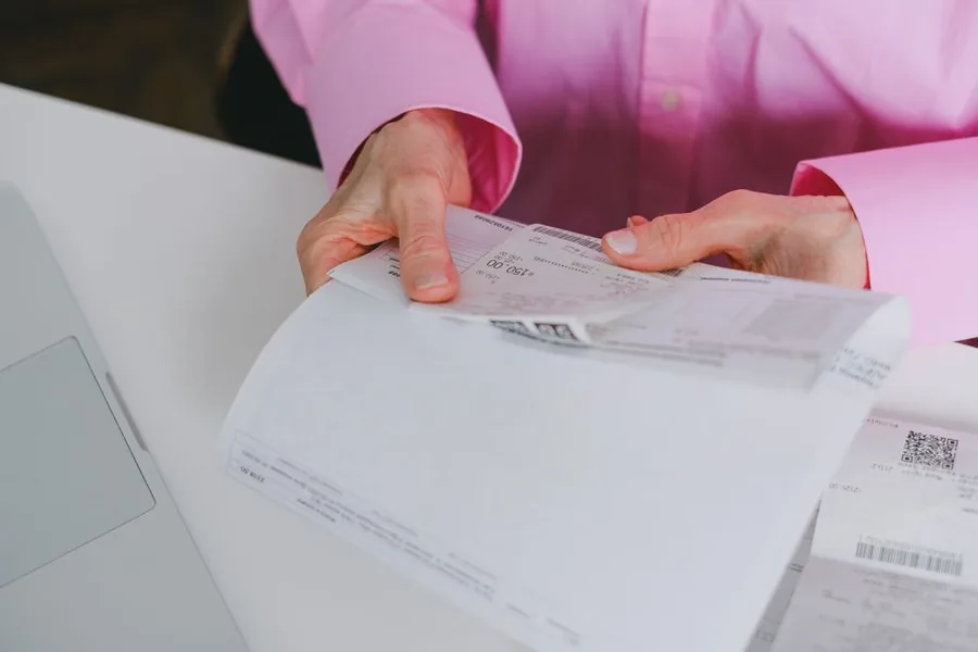 A Vinted reseller sorting through printed receipts and invoices to total up allowable business expenses