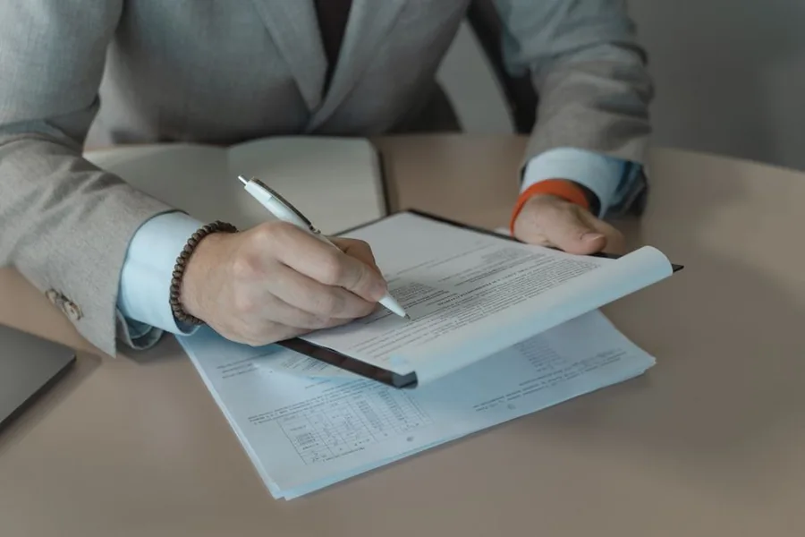 A company director signing employee share scheme paperwork at an office desk A company director signing employee share scheme paperwork at an office desk