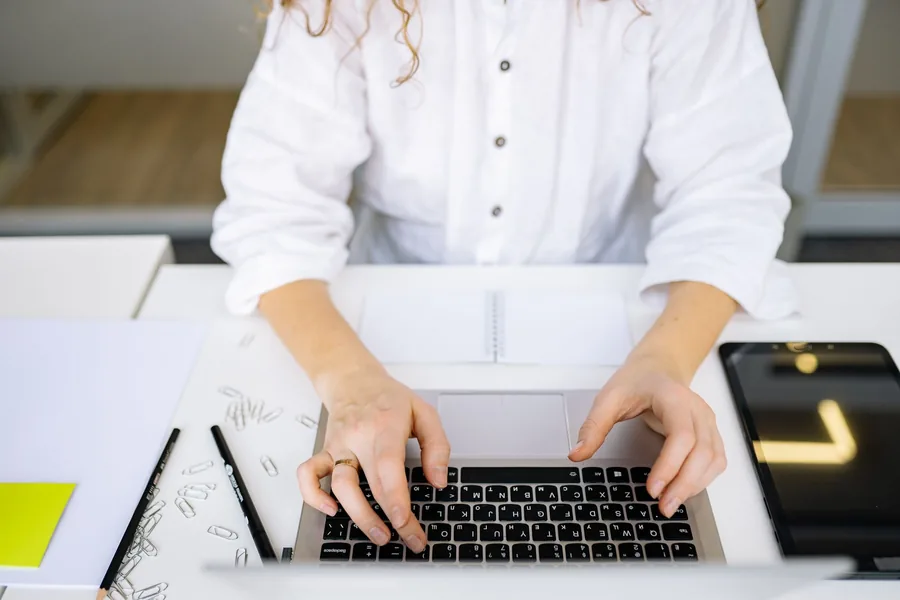 Close-up of a small business owner typing on a laptop at a tidy desk while preparing the company accounts