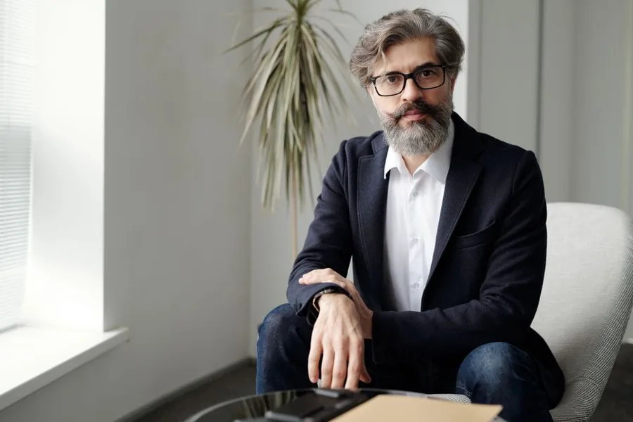 A UK company director in a smart jacket seated in a modern office, considering the tax-free perks available to him