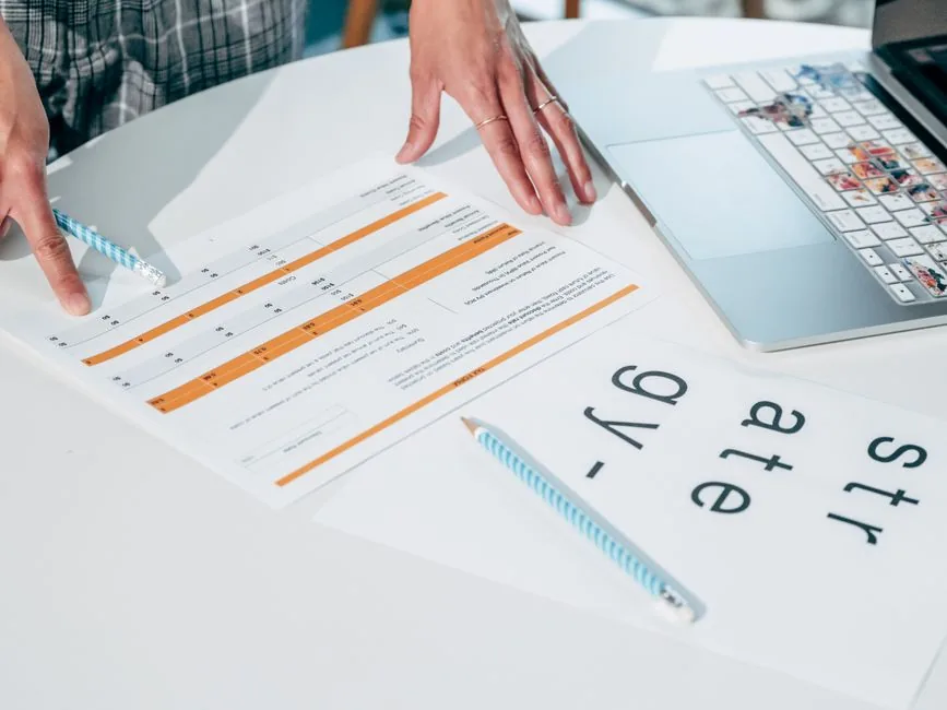 Checking the pay and tax figures on an end-of-year statement before filing, laptop open alongside Checking the pay and tax figures on an end-of-year statement before filing, laptop open alongside